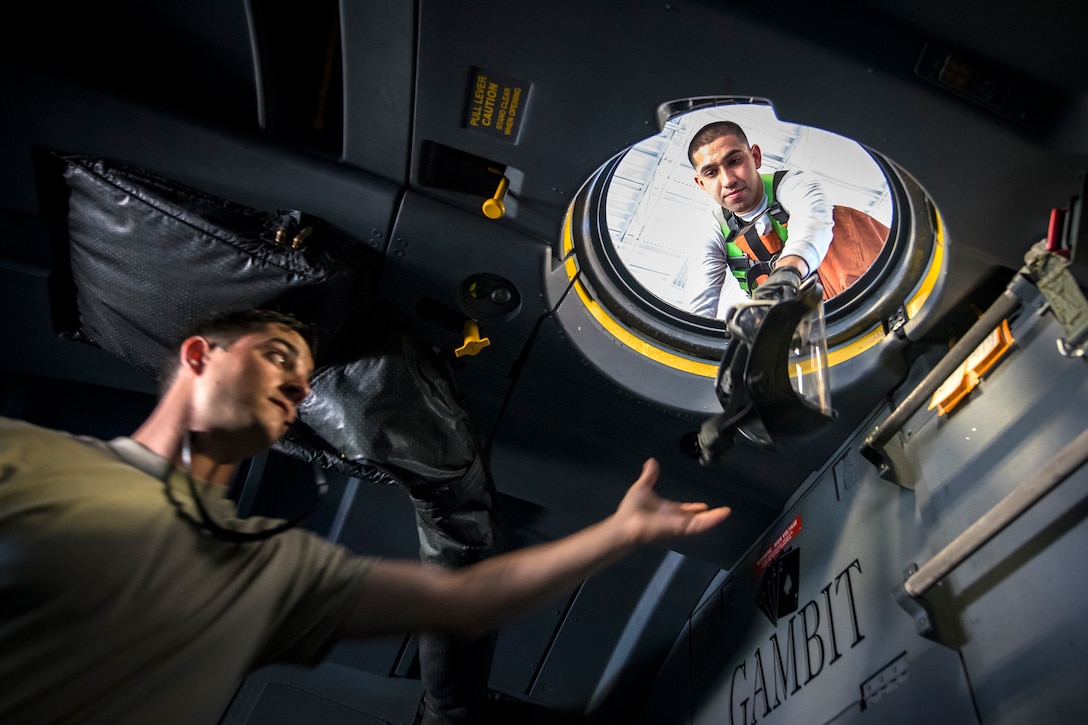 Airman 1st Class Jesse Orosco, right, 71st Aircraft Maintenance Unit (AMU) crew chief, passes a protectant helmet to Staff Sgt. Ryan Culbertson, 71st AMU crew chief, during an HC-130J Combat King II wash, May 7, 2018, at Moody Air Force Base, Ga. Upon return from a deployment or every 180 days, HC-130’s are thoroughly cleaned and inspected as part of routine upkeep and to ensure its respective components are in working condition. (U.S. Air Force photo by Airman 1st Class Eugene Oliver)