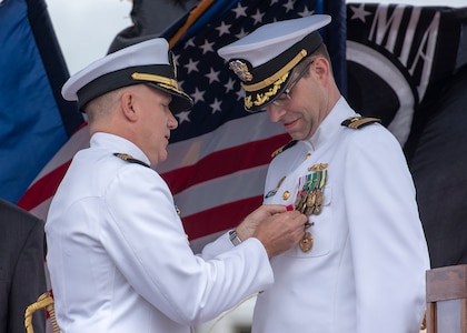 Capt. Richard Seif, commander, Submarine Squadron One, presents a Legion of Merit to Cmdr. Eric J. Rozek, commanding officer of the Virginia-class fast-attack submarine USS Mississippi (SSN 782), during a change of command ceremony on the submarine piers in Joint Base Pearl Harbor-Hickam, May 8. (U.S. Navy photo by Mass Communication Specialist 2nd Class Michael Lee/Released)