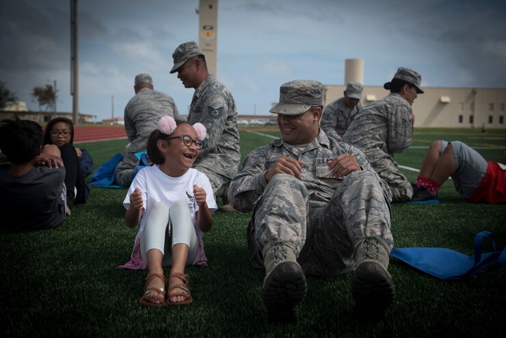 U.S. Air Force Staff Sgt. Joshua Anderson, right, assigned to the U.S. Air Force Reserve’s 44th Aerial Port Squadron, performs sit-ups with military children during Operation Inafa’ Maolek at Andersen Air Force Base, May 5, 2018.