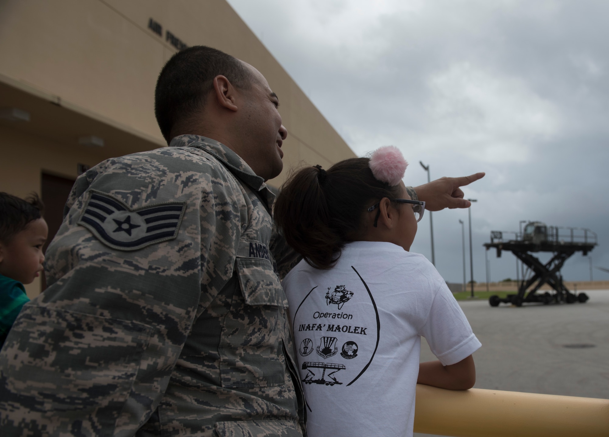 U.S. Air Force Staff Sgt. Joshua Anderson, left, assigned to the U.S. Air Force Reserve’s 44th Aerial Port Squadron, watches an aerial port equipment demonstration with military children during Operation Inafa’ Maolek at Andersen Air Force Base, May 5, 2018.