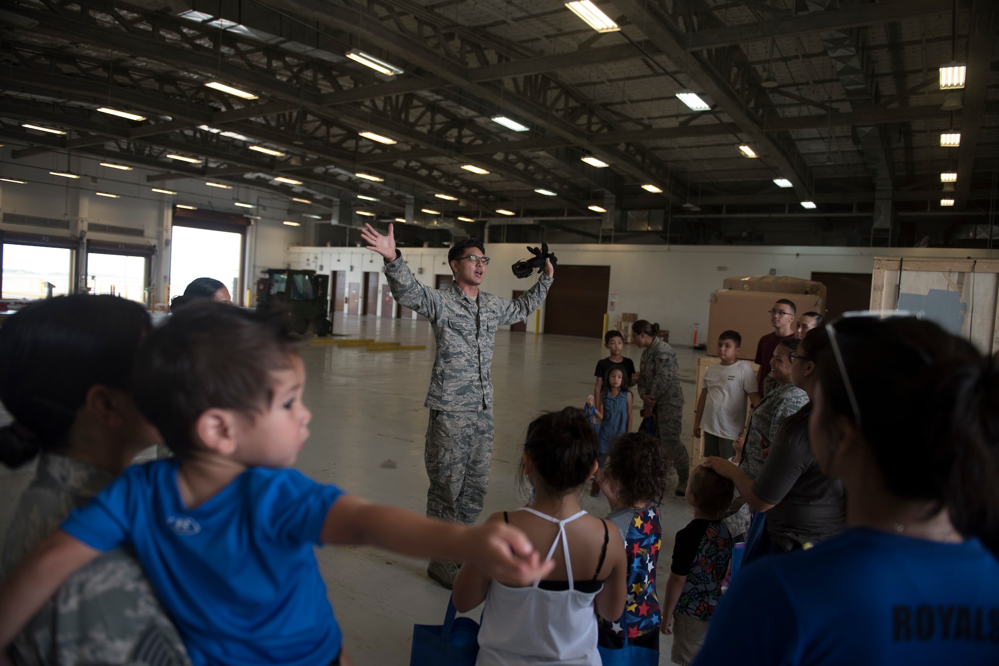 U.S. Air Force Tech. Sgt. Joshua Sablan, assigned to the U.S. Air Force Reserve’s 44th Aerial Port Squadron, welcomes military families to the aerial port warehouse during Operation Inafa’ Maolek at Andersen Air Force Base, May 5, 2018.