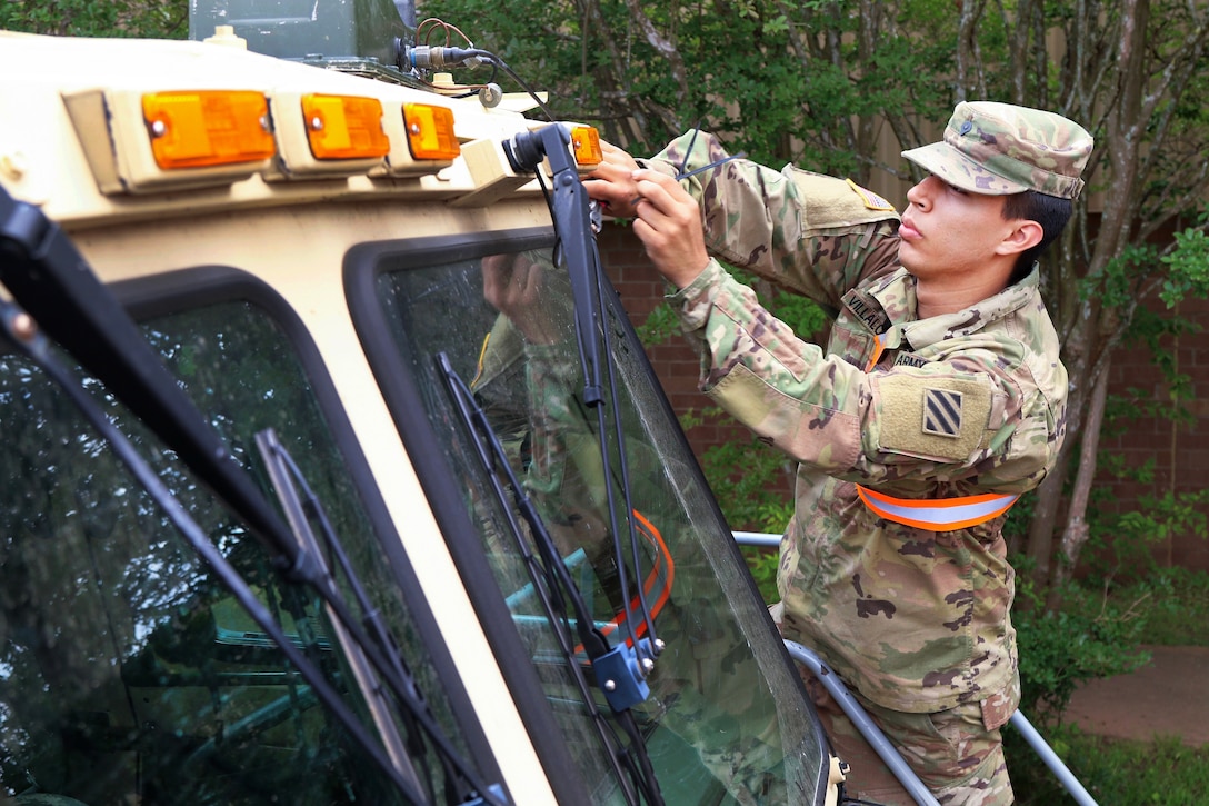 A soldier ties down Multiple Integrated Laser Engagement System to a tactical vehicle.