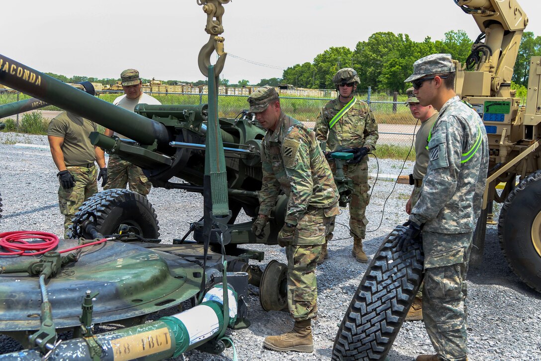A soldier prepares to traverse the barrel of an M119A2 howitzer.