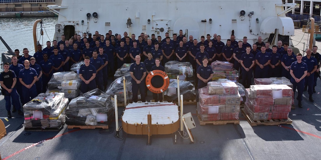 Group photo of the crew of the Coast Guard Cutter James alongside 6 tons of cocaine seized in counterdrug operations.