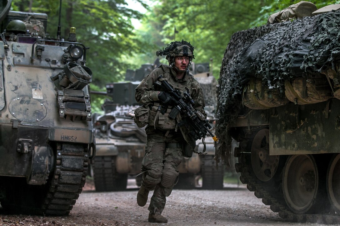 A soldier dismounts from an M2 Bradley fighting vehicle.