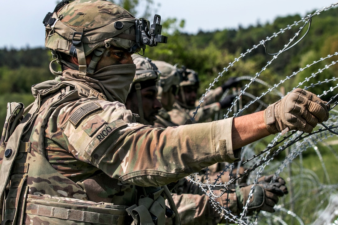 A soldier places concertina wire to build a secured perimeter.