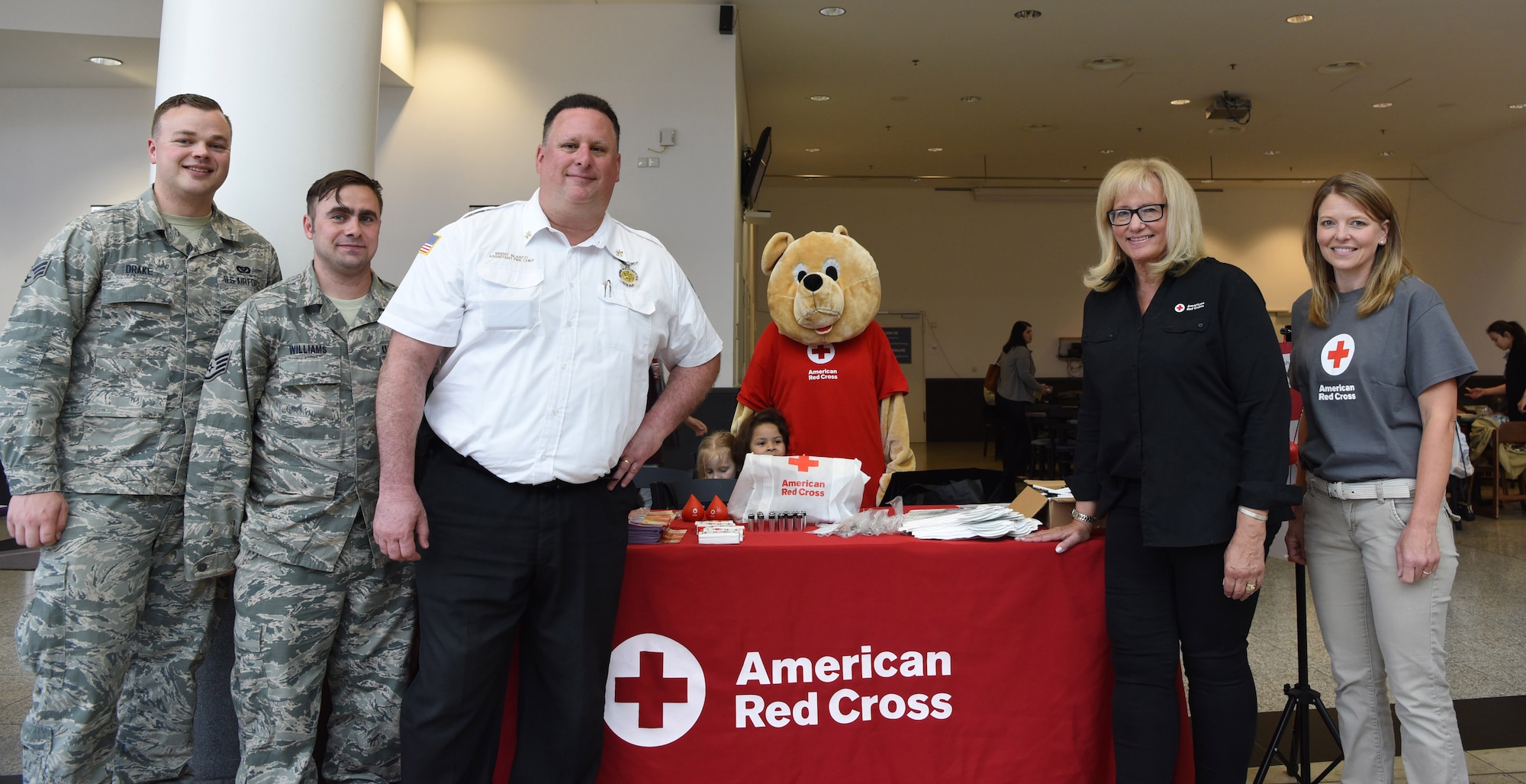 Kaiserslautern Military Community Fire Emergency Services members and American Red Cross members pose in front of their booth at the Kaiserslautern Military Community Center on Ramstein Air Base, Germany, May 11, 2018. The team handed out 200 free smoke detector batteries in an effort to raise awareness about the importance of fire safety.
