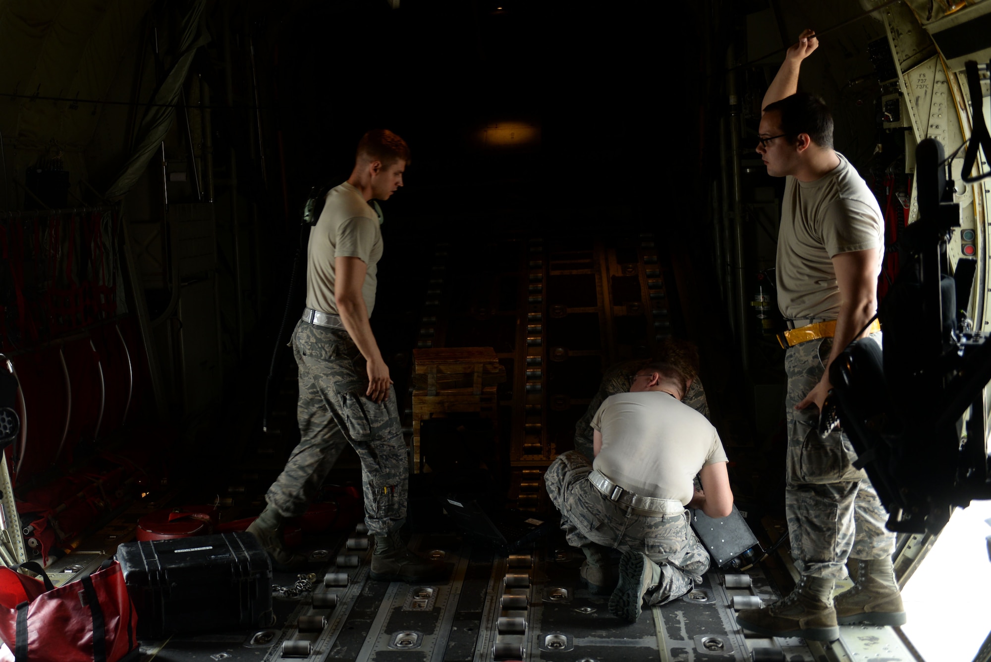 Three men in the Airman Battle Uniform stand in a C-130J aircraft.