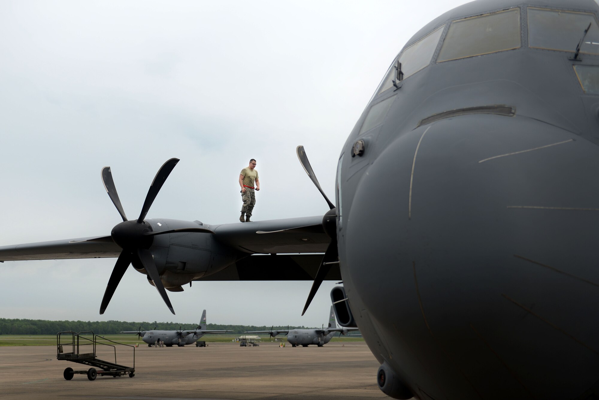 A man in the Airman Battle Uniform walks on the wing of a C-130J aircraft.