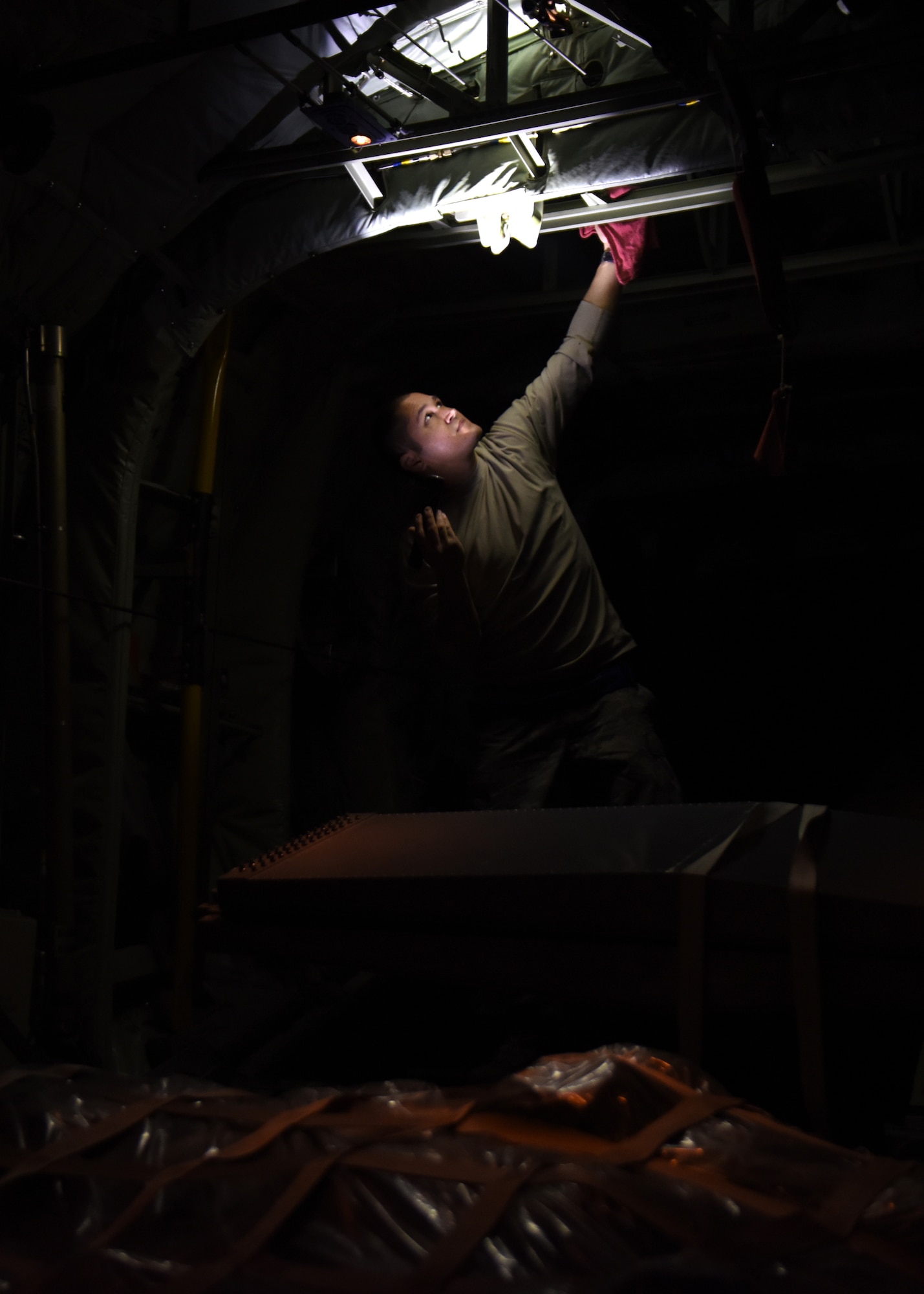 A male works in the dark at night on a C-130J.