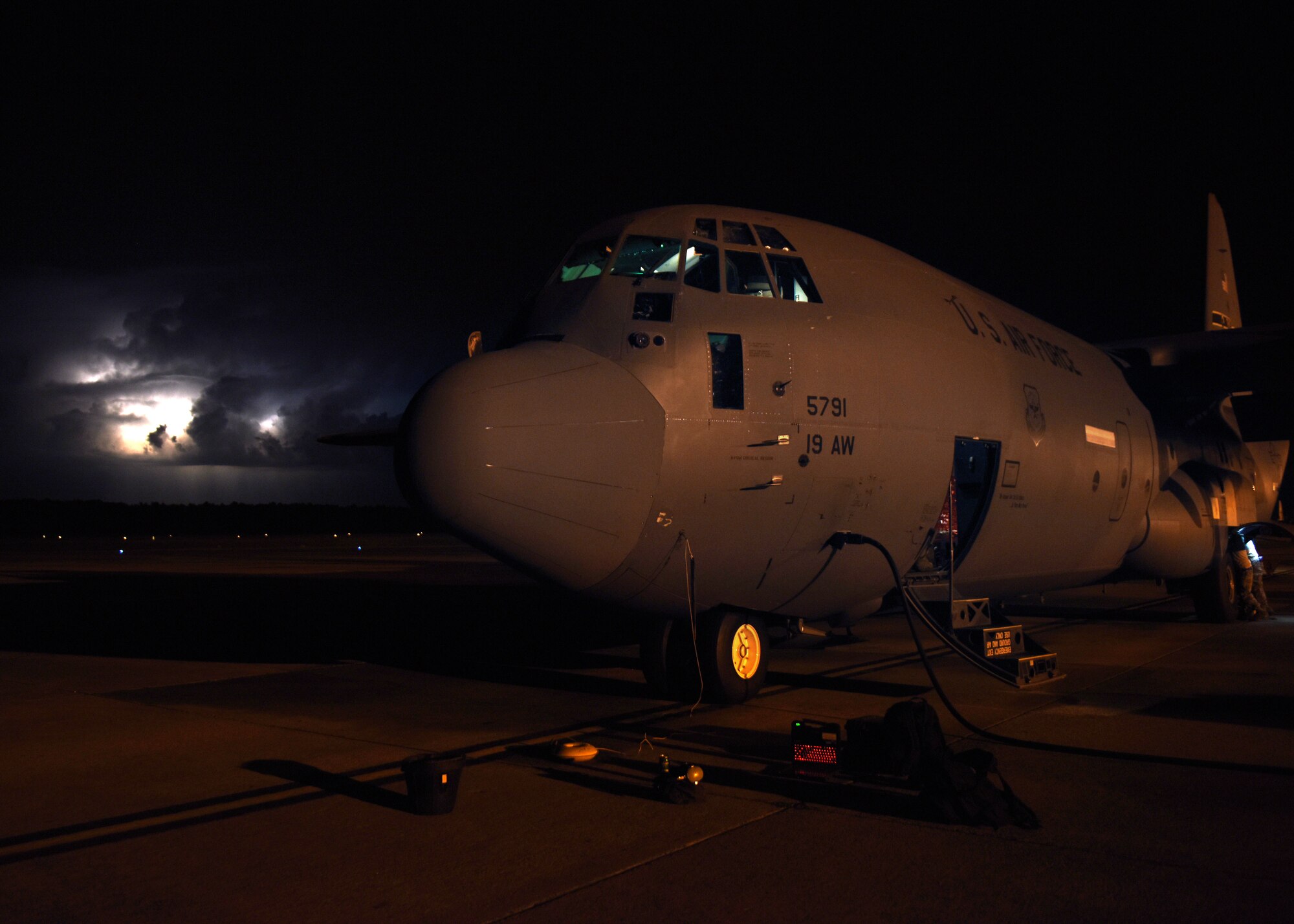 A male works in the dark at night on a C-130J.