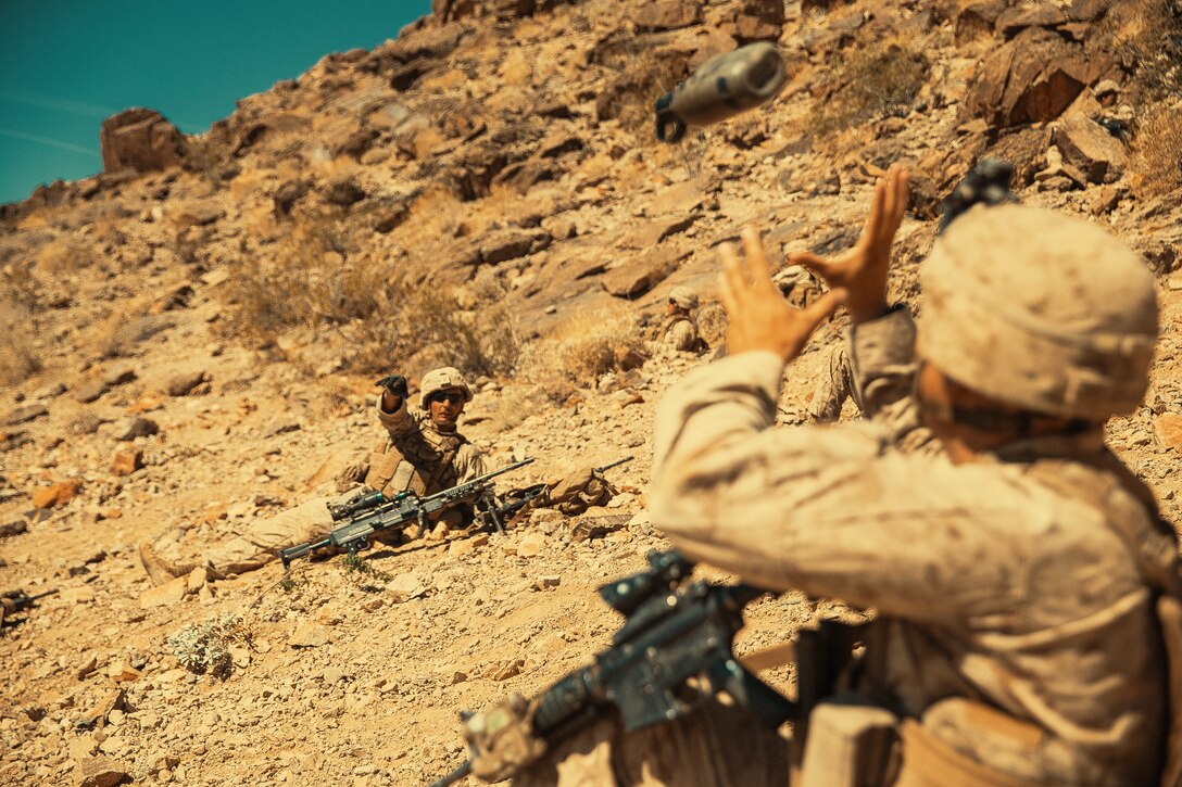 A Marine with 3rd Battalion, 4th Marine, 7th Marine Regiment, 1st Marine Division, tosses a fellow Marine his canteen at Range 400 during Integrated Training Exercise 3-18 aboard the Marine Corps Air Ground Combat Center, Twentynine Palms, Calif., May 7, 2018. The purpose of ITX is to create a challenging, realistic training environment that produces combat-ready forces capable of operating as an integrated Marine Air Ground Task Force. (U.S. Marine Corps photo by Lance Cpl. Isaac Cantrell)