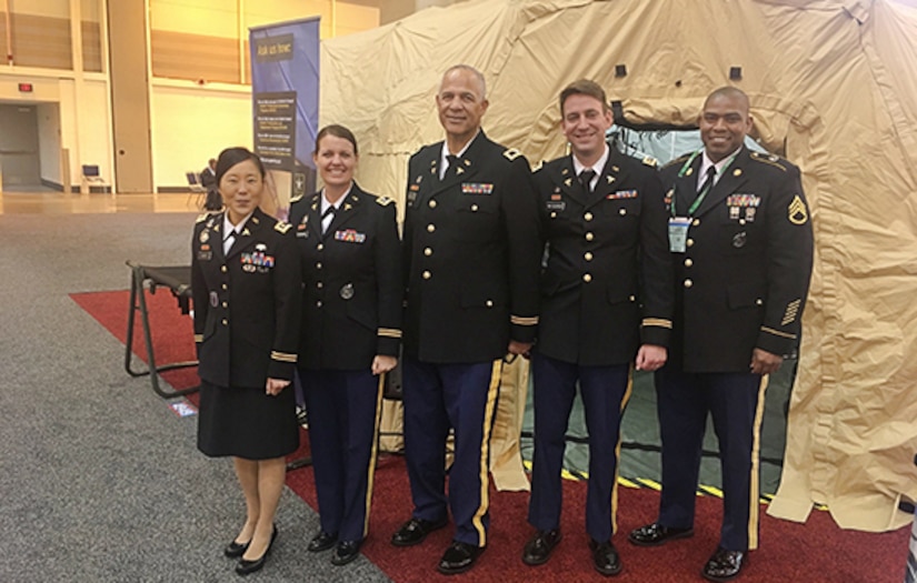 Five medical Soldiers standing front of a medical tent display