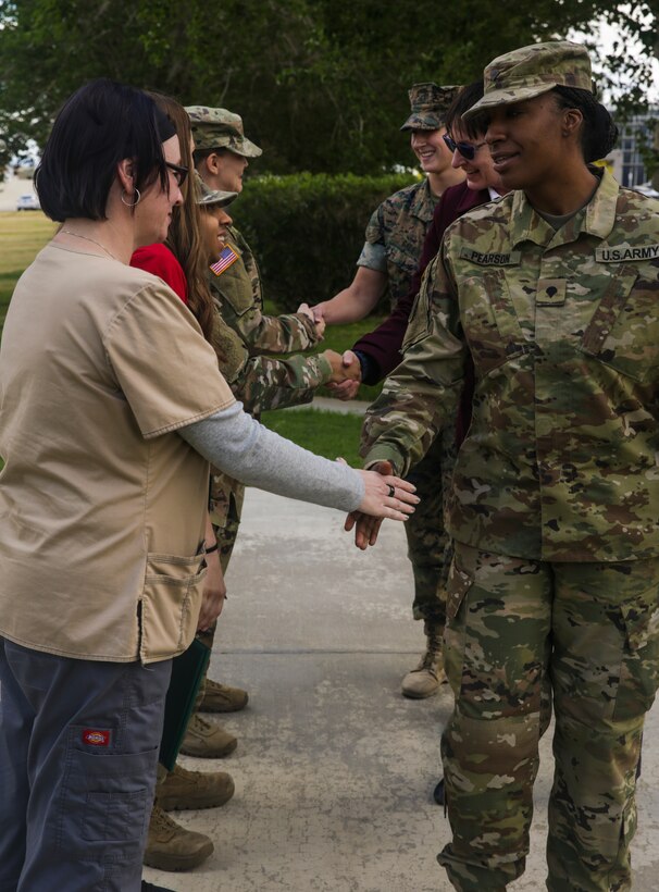 People congratulate soldiers and civilians with the Army's Mojave Branch Veterinary Services, U.S. Army Public Health after they recieved the Army Commedation Medal and the Army's Achievment Medal for Civilian Service at the flag pole aboard the Marine Corps Air Ground Combat Center, Twentynine Palms, Calif., May 2, 2018. The soldiers and civilians received the medals for assisting and stabilizing a motorcyclist involved in a car accident in the local community. (U.S. Marine Corps photo by Lance Cpl. Dave Flores)