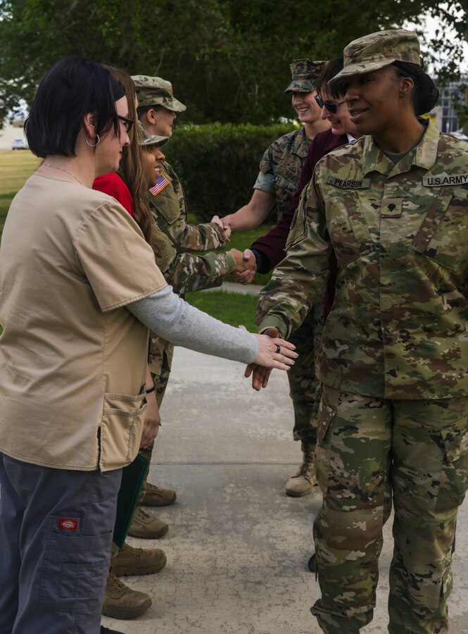 People congratulate soldiers and civilians with the Army's Mojave Branch Veterinary Services, U.S. Army Public Health after they recieved the Army Commedation Medal and the Army's Achievment Medal for Civilian Service at the flag pole aboard the Marine Corps Air Ground Combat Center, Twentynine Palms, Calif., May 2, 2018. The soldiers and civilians received the medals for assisting and stabilizing a motorcyclist involved in a car accident in the local community. (U.S. Marine Corps photo by Lance Cpl. Dave Flores)