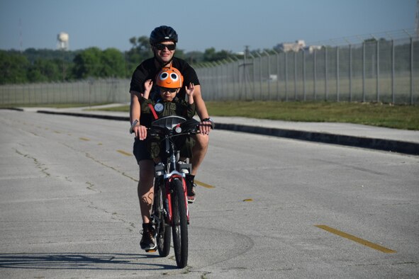 U.S. Air Force Master Sgt. Jay Mejia, 433rd Aeromedical Evacuation Squadron flight medic, and his son Jayden, 4, finish a 10-mile bike ride during the 433rd Airlift Wing Family Fun Day at Joint Base San Antonio-Lackland, Texas, May 6, 2018. Wing members brought their family and friends to enjoy free food, drinks, games, a tour of the C-5M Super Galaxy aircraft and fellowship during the annual event. (U.S. Air Force photo by Tech. Sgt. Carlos J. Trevino)