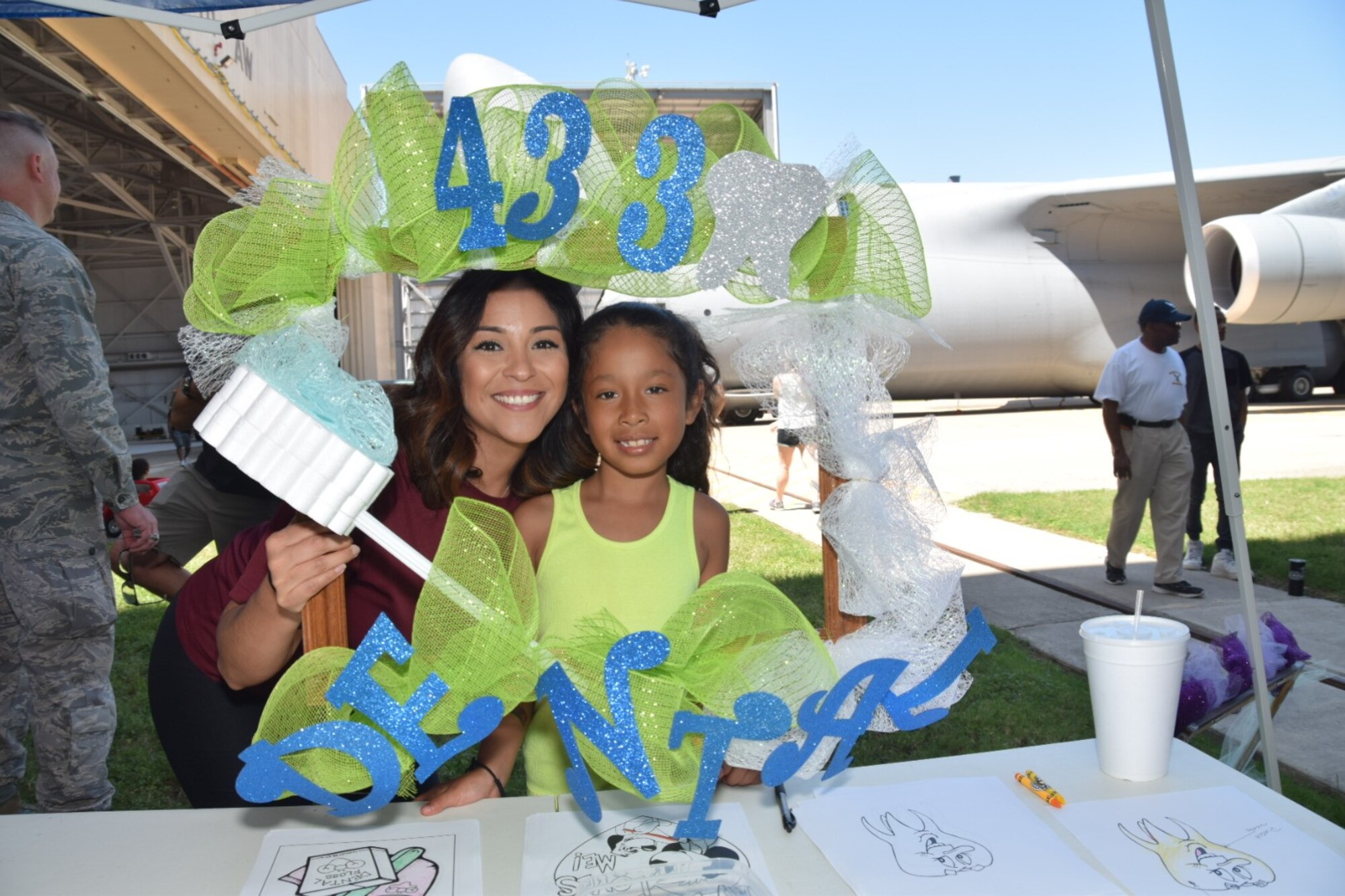U.S. Air Force Senior Airman Jessica Bravo, 433rd Aerospace Medical Squadron dental technician, poses for a photo with Cypress Aguayo, 7, daughter of Army Sgt. 1st Class (Ret.) Saul Aguayo, at the annual 433rd Airlift Wing Family Fun Day May 6, 2018, at Joint Base San Antonio-Lackland, Texas. The Alamo Wing dental technicians were on hand to emphasize good oral hygiene to children visiting the annual event. (U.S. Air Force photo by Tech. Sgt. Carlos J. Trevino)