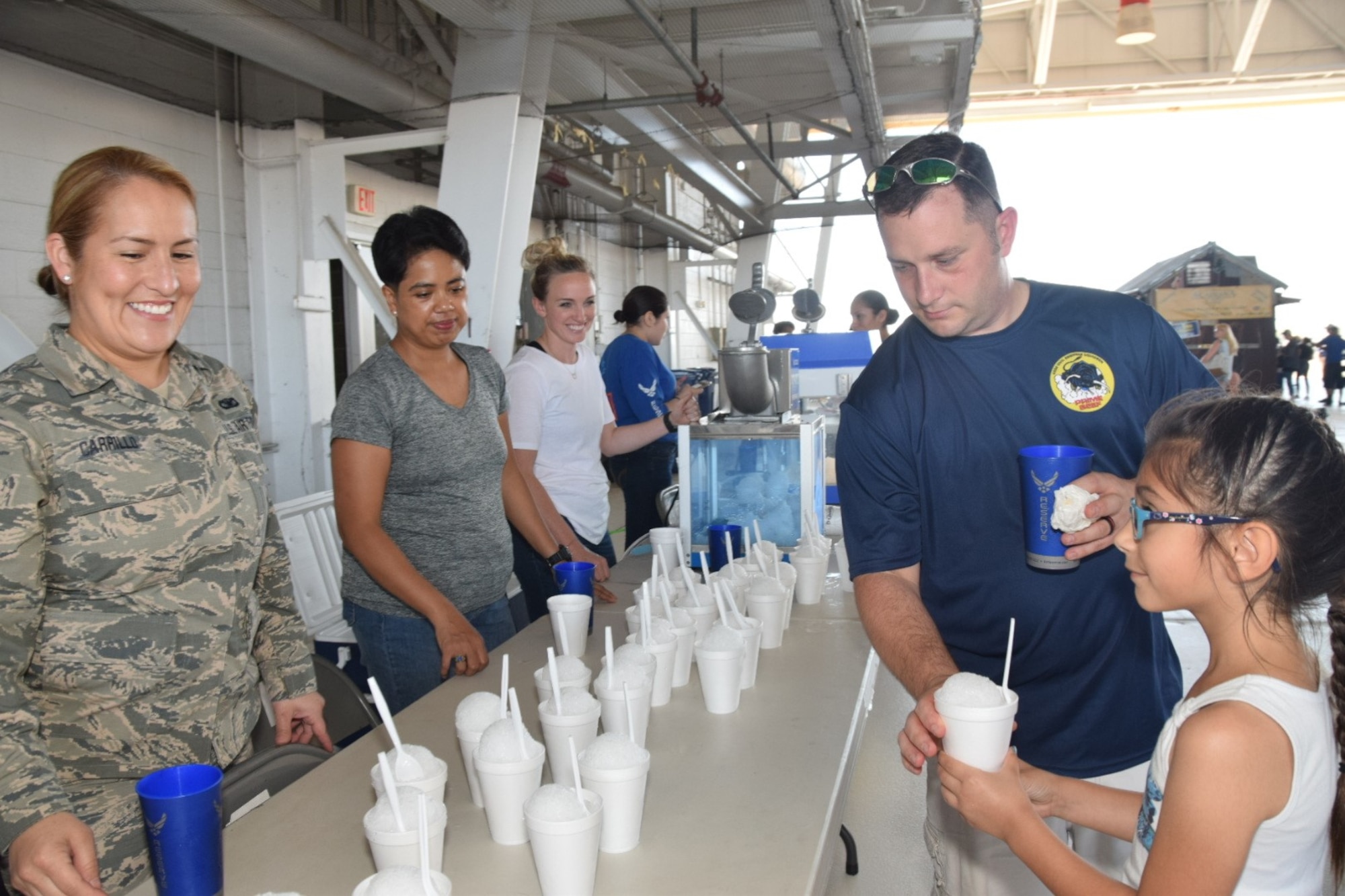 U.S. Air Force Senior Airman April Carrillo, 433rd Security Force member, serves up a snow cone to Master Sgt. Jonathan Boyd, 433rd Civil Engineering Squadron fire fighter, and his daughter Alina, age 7, during the 433rd Airlift Wing  Family Fun day at Joint Base San Antonio-Lackland, Texas May 6, 2018. Free food, refreshments, games and static tours of vehicles and aircraft were part of the annual event. (U.S. Air Force photo by Tech. Sgt. Carlos J. Trevino)