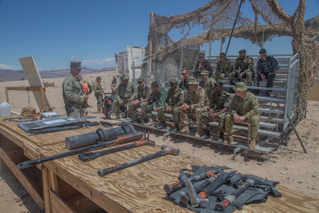 An exercise controller with Tactical Training Exercise Control Group briefs international military officers on breaching techniques at Range 220 aboard the Marine Corps Air Ground Combat Center, Twentynine Palms, Calif., May 2, 2018. The international officers are students at the Command and Staff College, Marine Corps University, Marine Corps Base Quantico, Va., and are set to graduate June 6, 2018. (U.S. Marine Corps photo by Lance Cpl. Preston L. Morris)