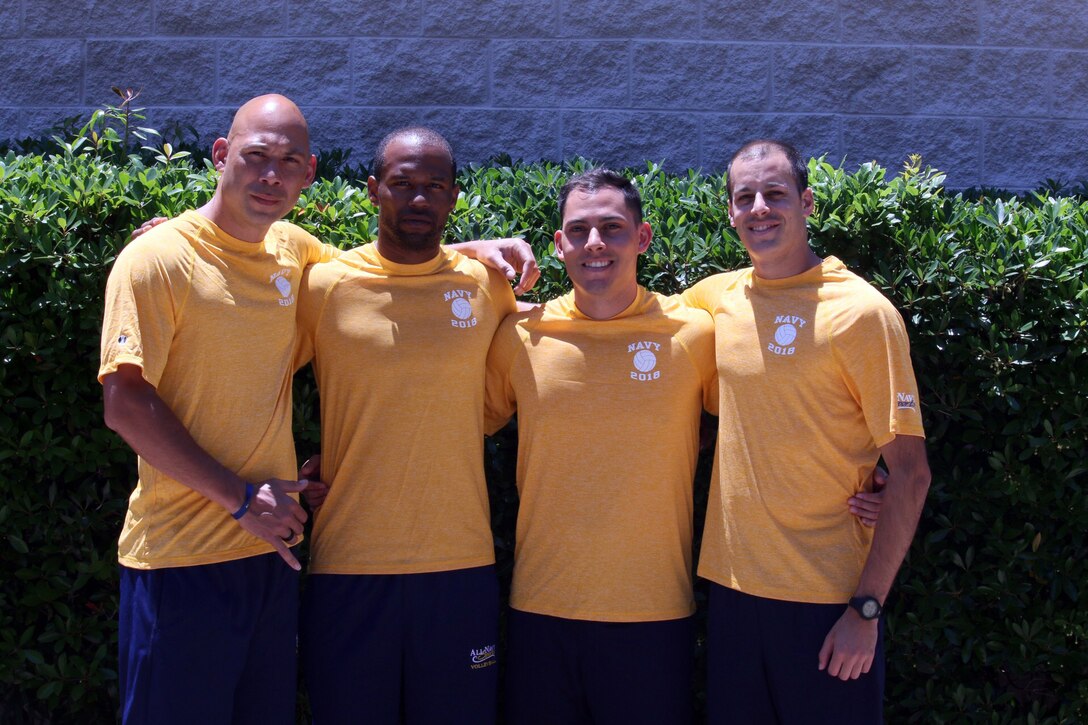 Four Navy volleyball players pose for a photo.