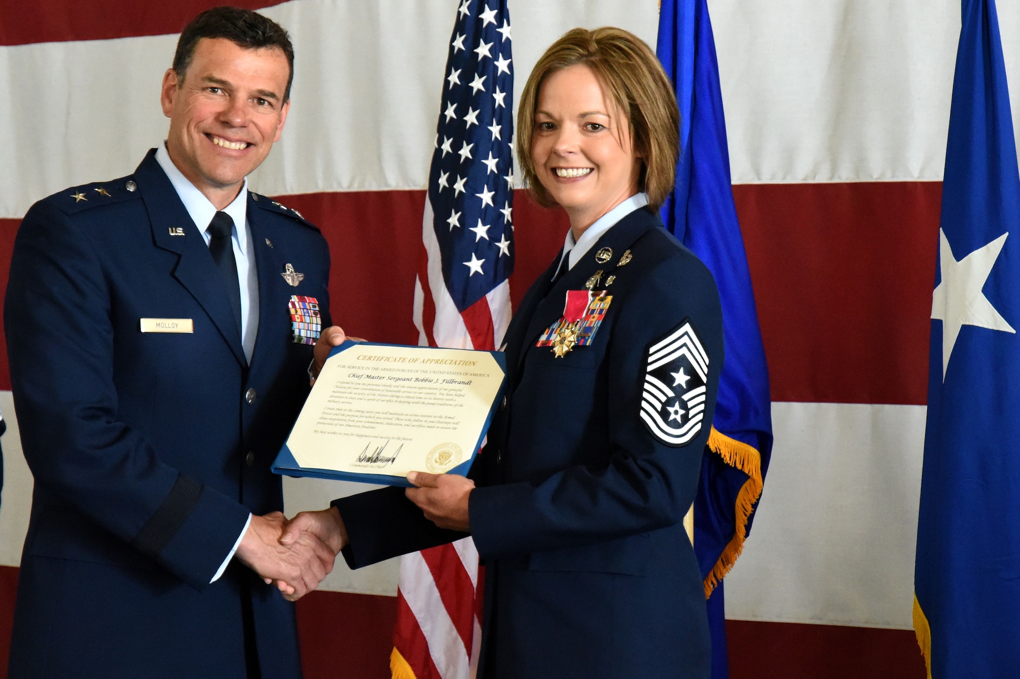 U.S. Air Force Maj. Gen. Matthew Molloy, Air Force Operational Test and Evaluation Center commander, presents Chief Master Sgt. Bobbie Fillbrandt with a certificate of appreciation during her retirement ceremony at the Louis F. Garland Department of Defense Fire Academy on Goodfellow Air Force Base, Texas, May 10, 2018. The certificate presented was on behalf of President Donald Trump, expressing congratulations and thanks for all her service leading up to retirement. (U.S. Air Force photo by Airman 1st Class Seraiah Hines/Released)