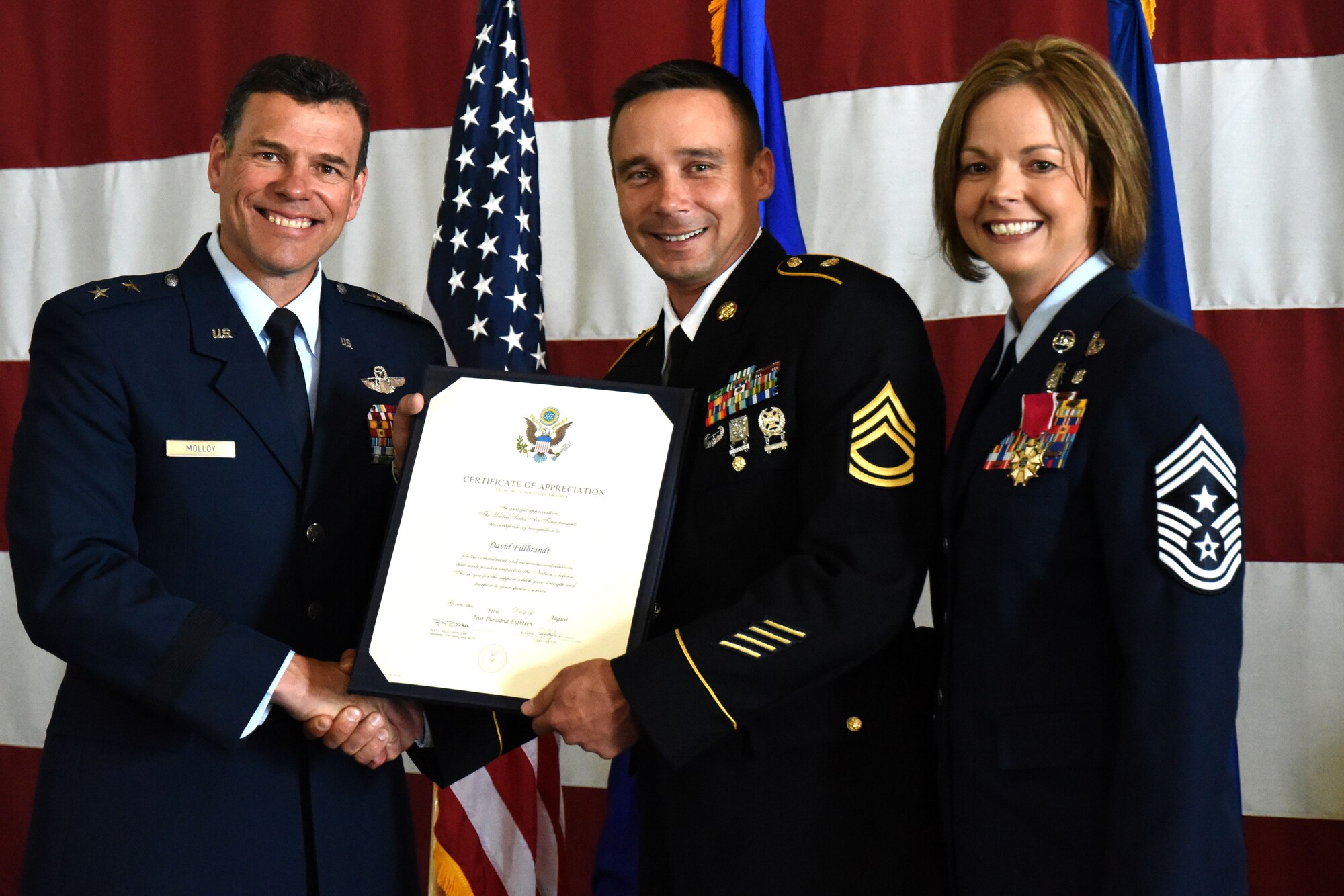 U.S. Air Force Maj. Gen. Matthew Molloy, Air Force Operational Test and Evaluation Center commander, presents U.S. Army Sgt. 1st Class David Fillbrandt, 344th Military Intelligence Battalion platoon sergeant, with a certificate of appreciation at U.S. Air Force Chief Master Sgt. Bobbie Fillbrandt’s retirement ceremony in the Louis F. Garland Department of Defense Fire Academy on Goodfellow Air Force Base, Texas, May 10, 2018. This certificate is presented to spouses of military members retiring to show the Air Force’s appreciation of their support throughout the military member’s career.  (U.S. Air Force photo by Airman 1st Class Seraiah Hines/Released)