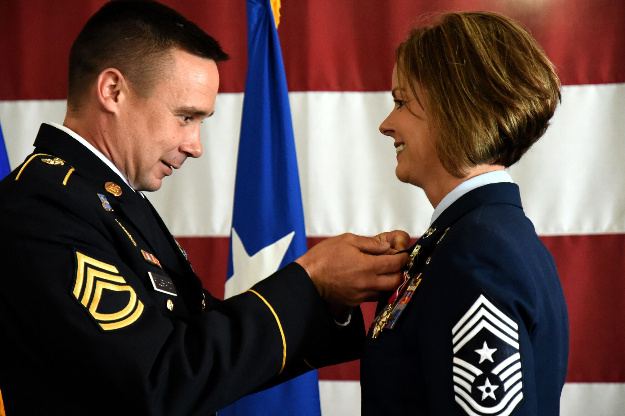 U.S. Army Sgt. 1st Class David Fillbrandt, 344th Military Intelligence Battalion platoon sergeant, places the retirement pin on his wife, U.S. Air Force Chief Master Sgt. Bobbie Fillbrandt, during her retirement ceremony at the Louis F. Garland Department of Defense Fire Academy on Goodfellow Air Force Base, Texas, May 10, 2018. This retirement pin commemorates Fillbrandt’s service in the U.S. Air Force. (U.S. Air Force photo by Airman 1st Class Seraiah Hines/Released)