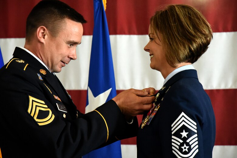 U.S. Army Sgt. 1st Class David Fillbrandt, 344th Military Intelligence Battalion platoon sergeant, places the retirement pin on his wife, U.S. Air Force Chief Master Sgt. Bobbie Fillbrandt, during her retirement ceremony at the Louis F. Garland Department of Defense Fire Academy on Goodfellow Air Force Base, Texas, May 10, 2018. This retirement pin commemorates Fillbrandt’s service in the U.S. Air Force. (U.S. Air Force photo by Airman 1st Class Seraiah Hines/Released)