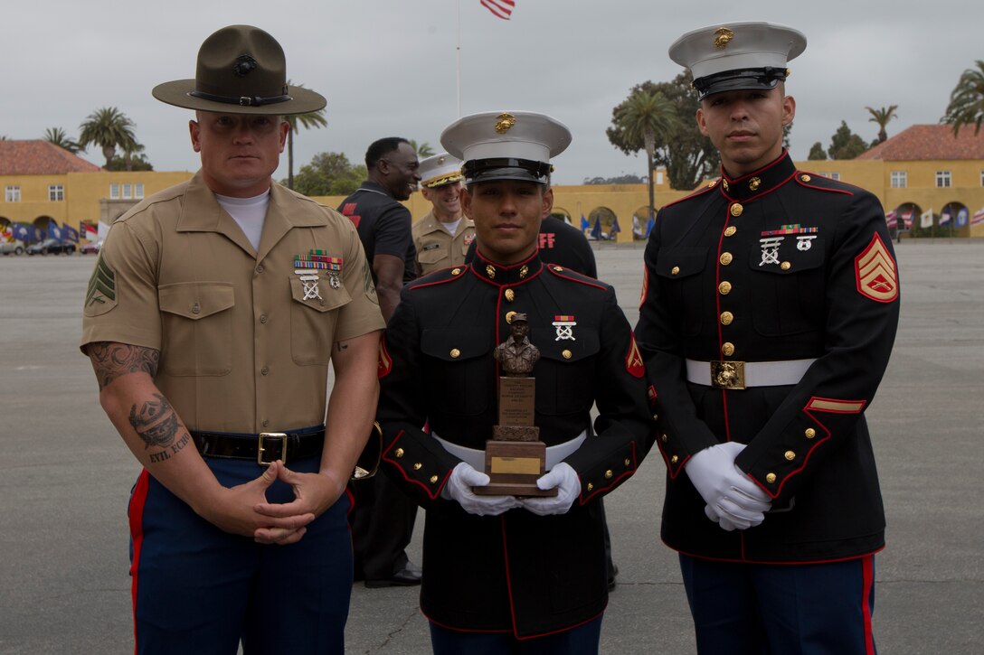 U.S. Marine Corps Lance Cpl. Jason Enriquez, center, with Company E, 2d Recruit Training Battalion (2D RTBN), Recruit Training Regiment (RTR), poses for a photo with his recruiter Staff Sgt. Elias Guzman, Recruiting Sub-Station Fairfield, Recruiting Station San Francisco, CA, 12th Marine Corps District, and his senior drill instructor Sgt. Cameron M. Ditch, with Company E, 2D RTBN, RTR, after a graduation ceremony at Marine Corps Recruit Depot San Diego, Calif., May. 11, 2018. Enriquez received the Chesty Puller award and was named company honor graduate from Company E, 2D RTBN. (U.S. Marine Corps photo by Lance Cpl. Alexander L. Gist)