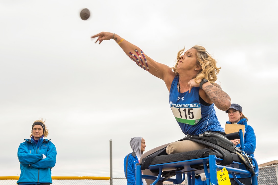 A person throws a shot put while seated on a platform.