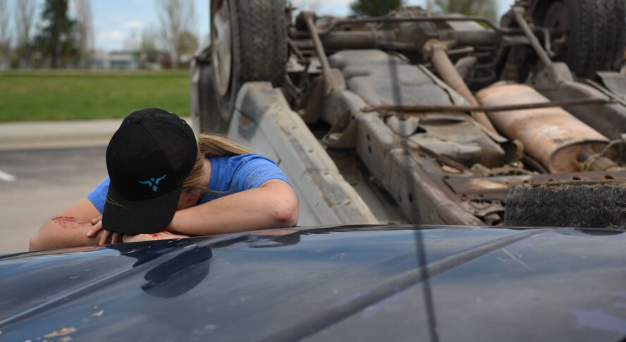 A student performer pretends to cry after causing a simulated vehicle accident at Douglas High School’s Freshman Impact in Box Elder S.D., May 9, 2018. An event called Freshmen Impact teaches young adults about the dangers of driving under the influence and distracted driving so they can make better decisions while behind the wheel. (U.S.  Air Force photo by Airman 1st Class Thomas Karol)