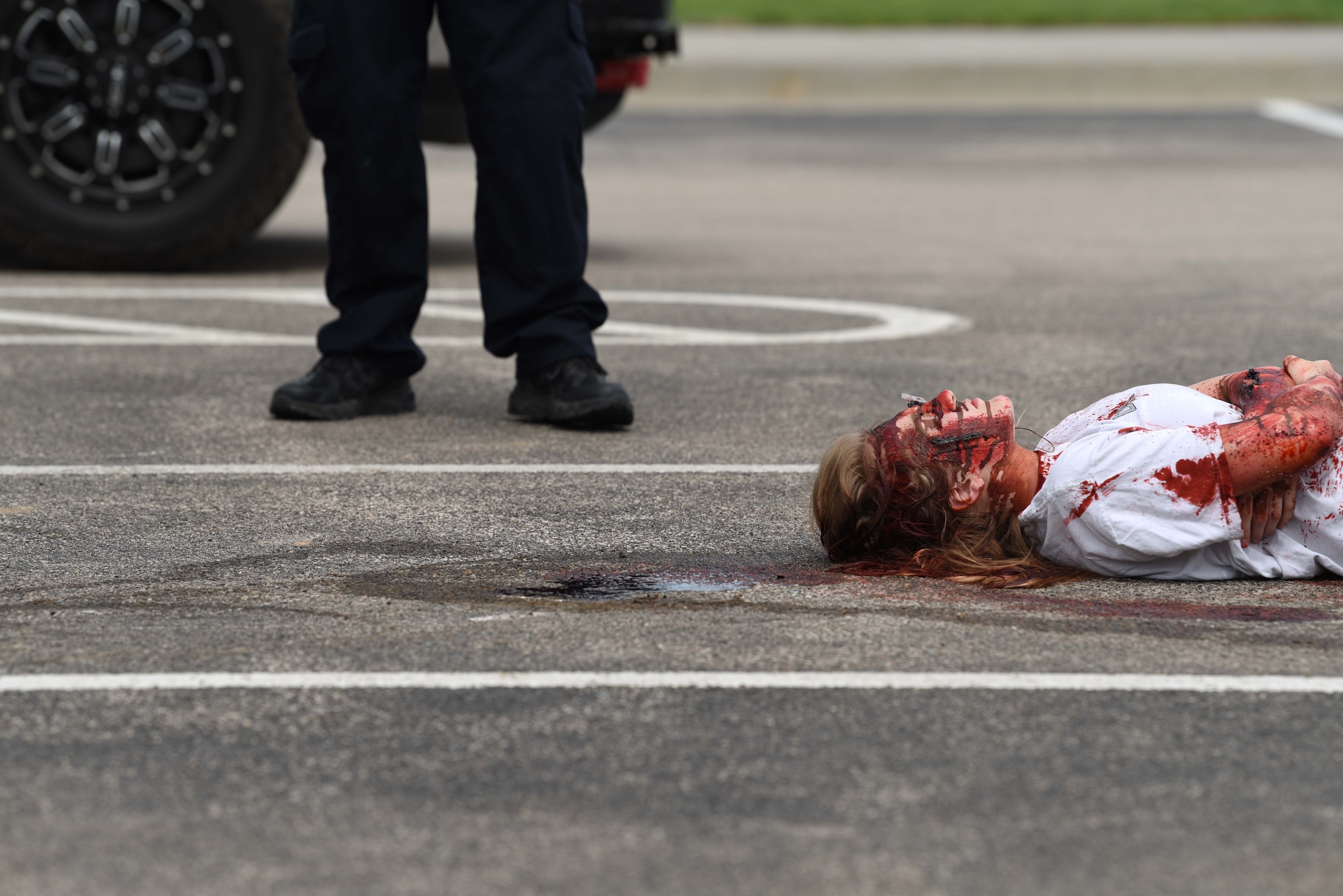 A student performer pretends to be injured after a simulated vehicle accident at Douglas High School’s Freshman Impact in Box Elder S.D., May 9, 2018. This event teaches young adults about the dangers of driving under the influence and distracted driving so they can make better decisions behind the wheel. (U.S.  Air Force photo by Airman 1st Class Thomas Karol)