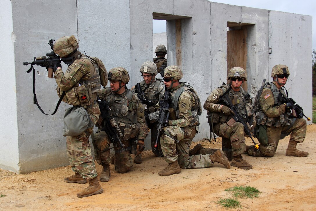 Soldiers provides security while team members search the inside of a building.