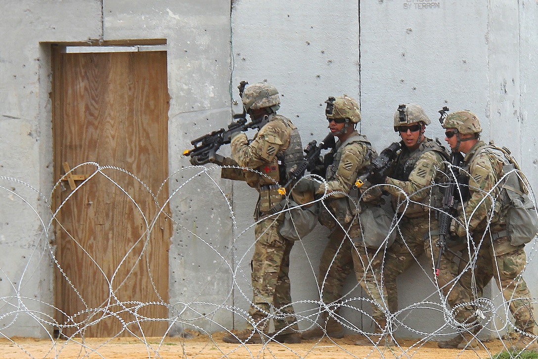Soldiers advance in stack formation along a building.