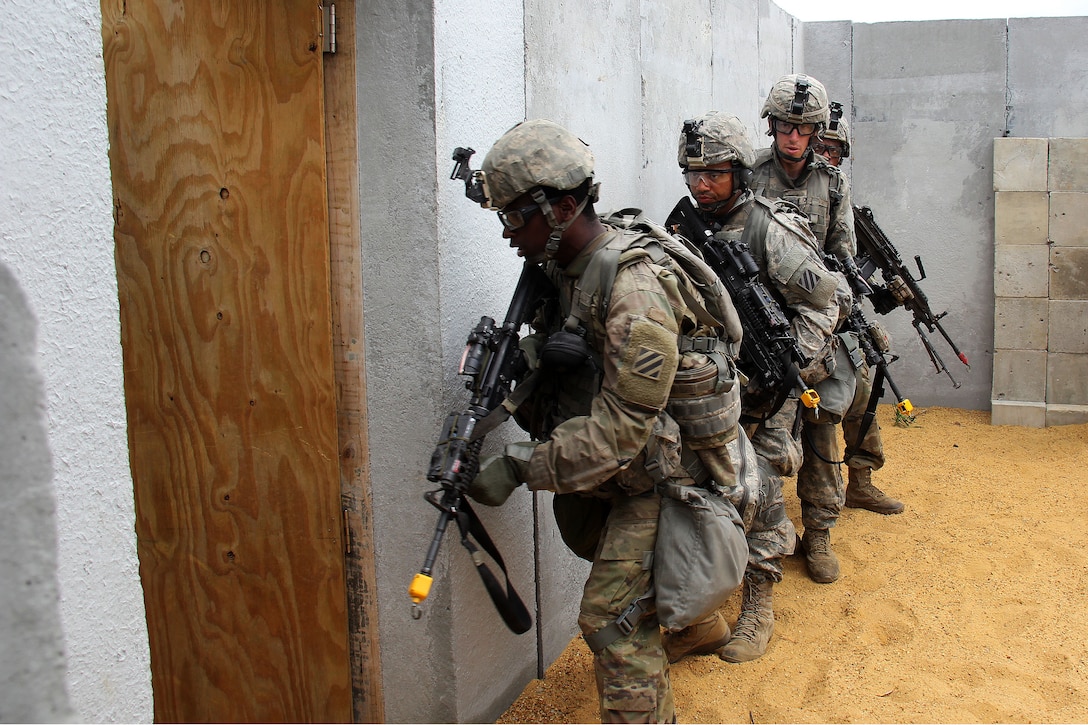 Soldiers in stack formation prepare to enter a building.