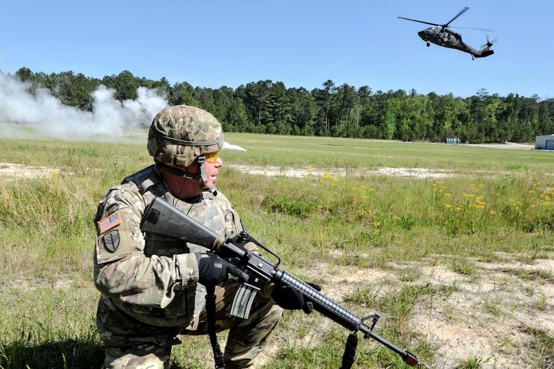 A soldier provides security while an approaching UH-60 Black Hawk helicopter lands.