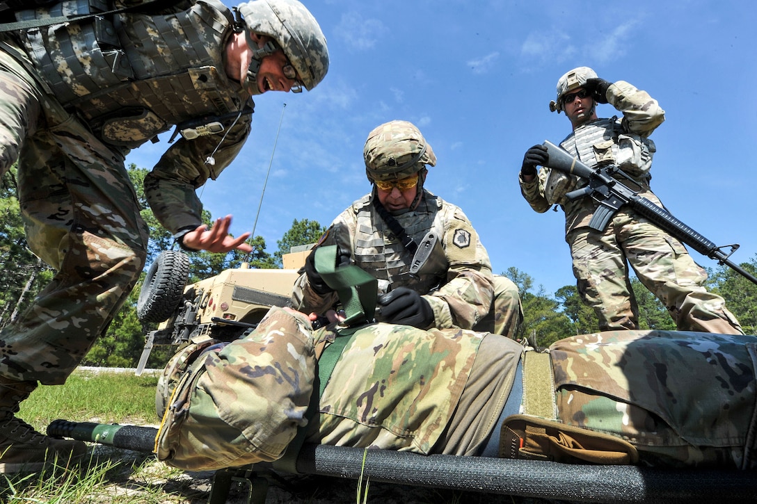 Soldiers secure a role-playing casualty onto a stretcher.