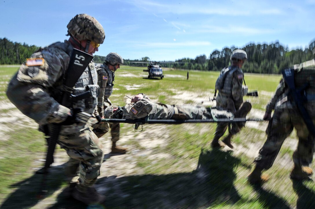 Soldiers transport a role-playing casualty on a stretcher.