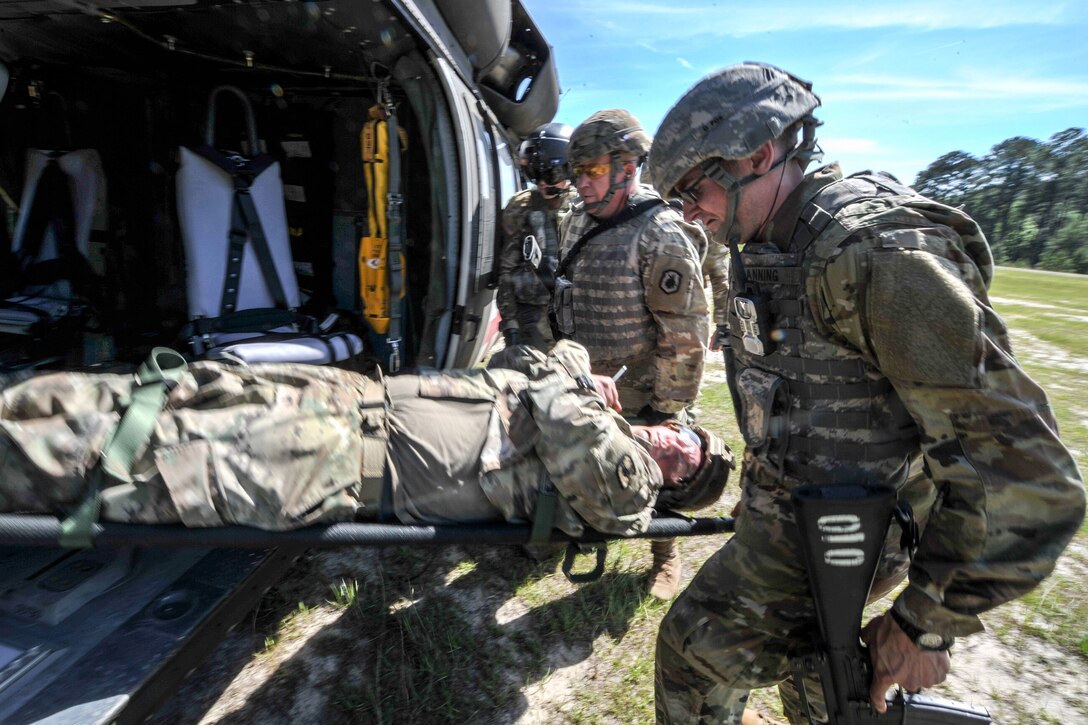 Soldiers load a role-playing casualty onto a UH-60 Black Hawk medevac helicopter.