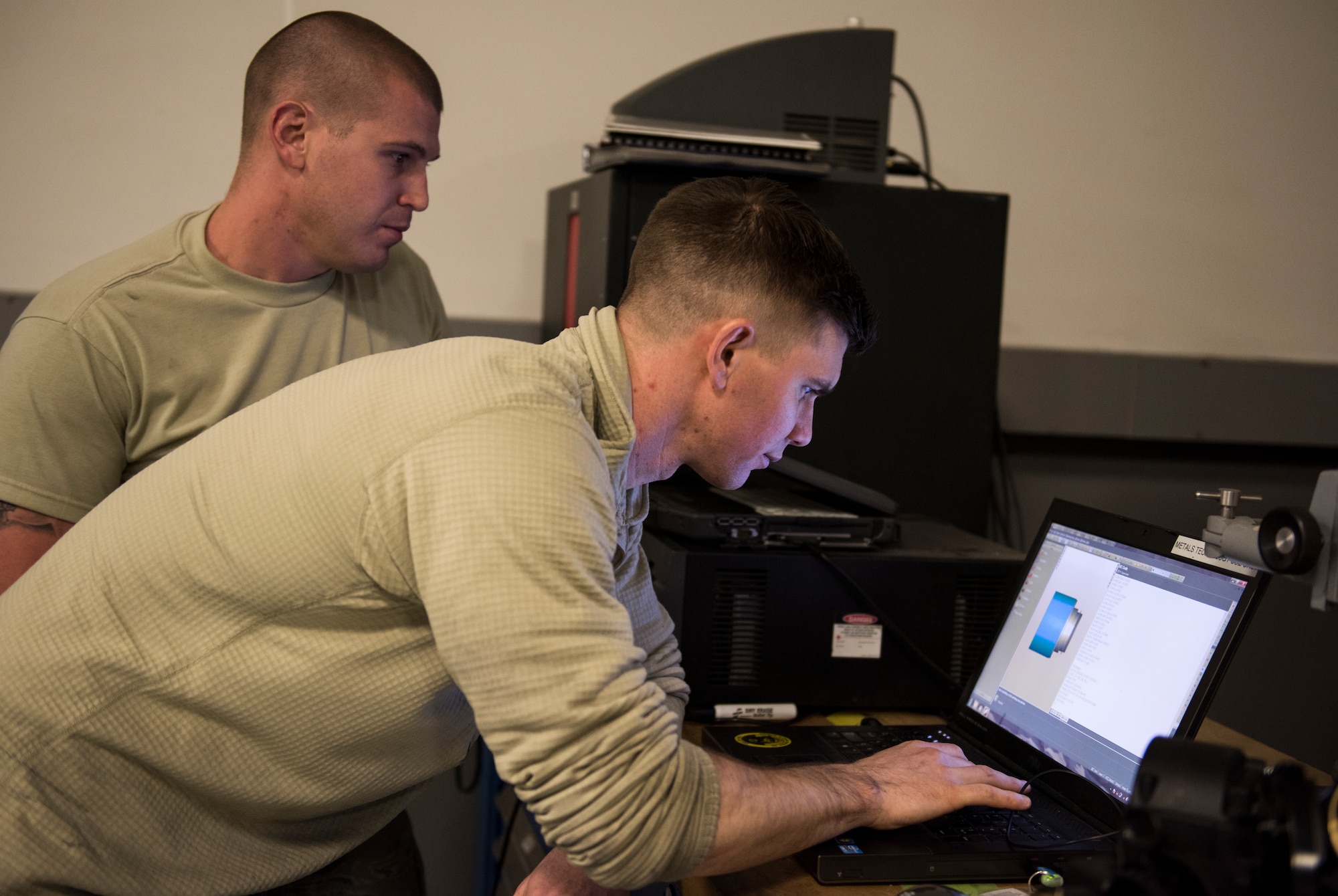 Staff Sgt. Steven Doucette, 92nd Maintenance Squadron aircraft metals technology shift lead, and Staff Sgt. Steven Bultemeier, 92nd MXS aircraft metals technology craftsman, work on code April 26, 2018, at Fairchild Air Force Base, Washington. The code instructs the Computer Numerically Controlled lathe on how to manufacture the main inlet fuel coupling. (U.S. Air Force photo/Senior Airman Sean Campbell)