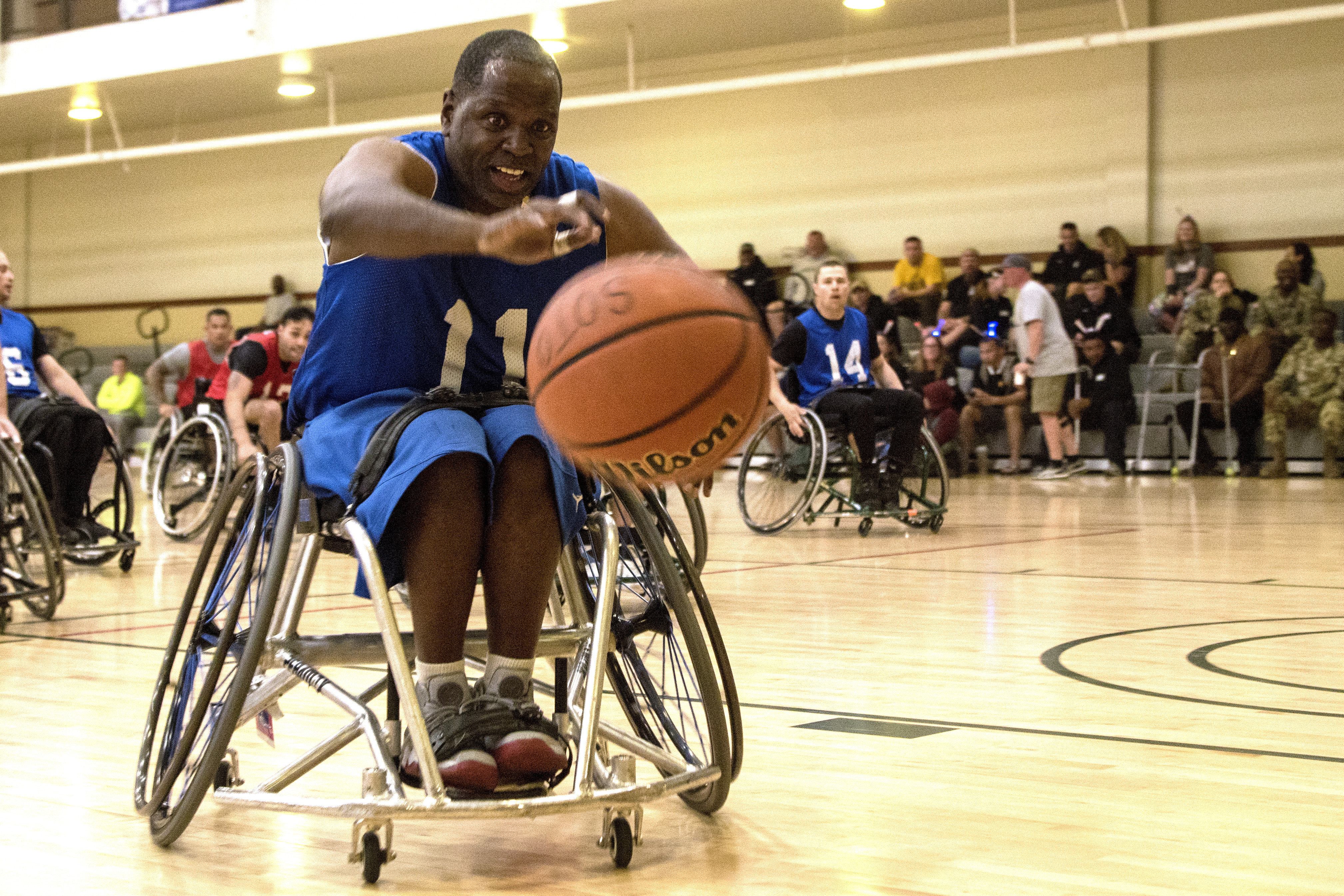 A person in a wheelchair leans towards a basketball.