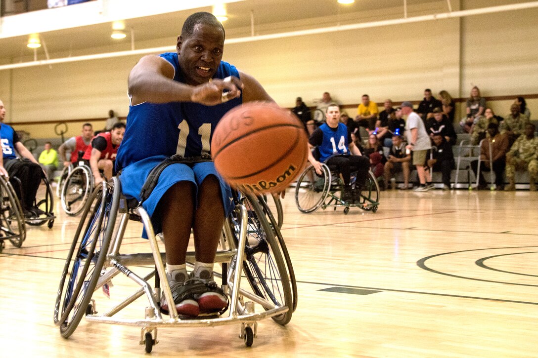 A person in a wheelchair leans towards a basketball.