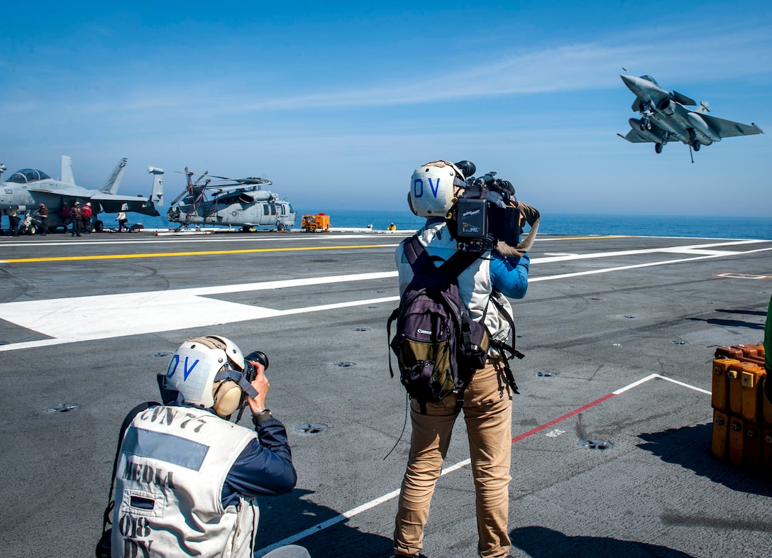 French media gather imagery and footage as a Rafale French navy aircraft attached to prepares to launch during flight operations aboard the aircraft carrier USS George H.W. Bush in the Atlantic Ocean.