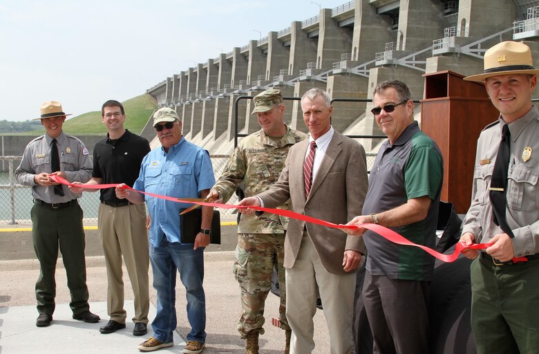 Park rangers held the ribbon as (2nd from left) Aaron Thompson, who serves as the Nebraska-Kansas Area Office Manager in McCook, Neb., and manages Reclamation projects in Nebraska, Kansas, and Colorado; John Nelsen, an owner and the President of Patterson Harbor Marina; Col. Douglas Guttormsen, commander of the Kansas City District, U.S. Army Corps of Engineers; Larry Janicek, Operations Manager of Harlan County Lake; and, Doug Wilson, City Administrator of Alma, Neb.; assisted in the cutting of the ribbon May 11, 2018.