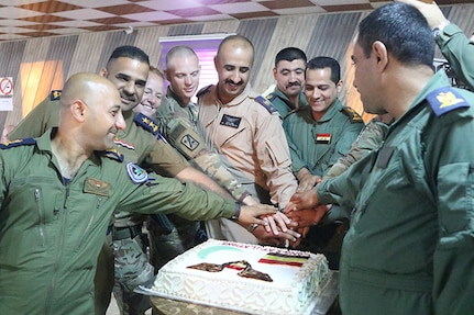 The 449th Combat Aviation Brigade, United Kingdom Training Team 1 (Armored Medical Regiment) and Iraqi army aviation medical staff celebrate the completion of the phase one 10-day aeromedical evacuation training course facilitated by the 449th CAB by collectively cutting cake at Camp Taji, Iraq, May 3, 2018.