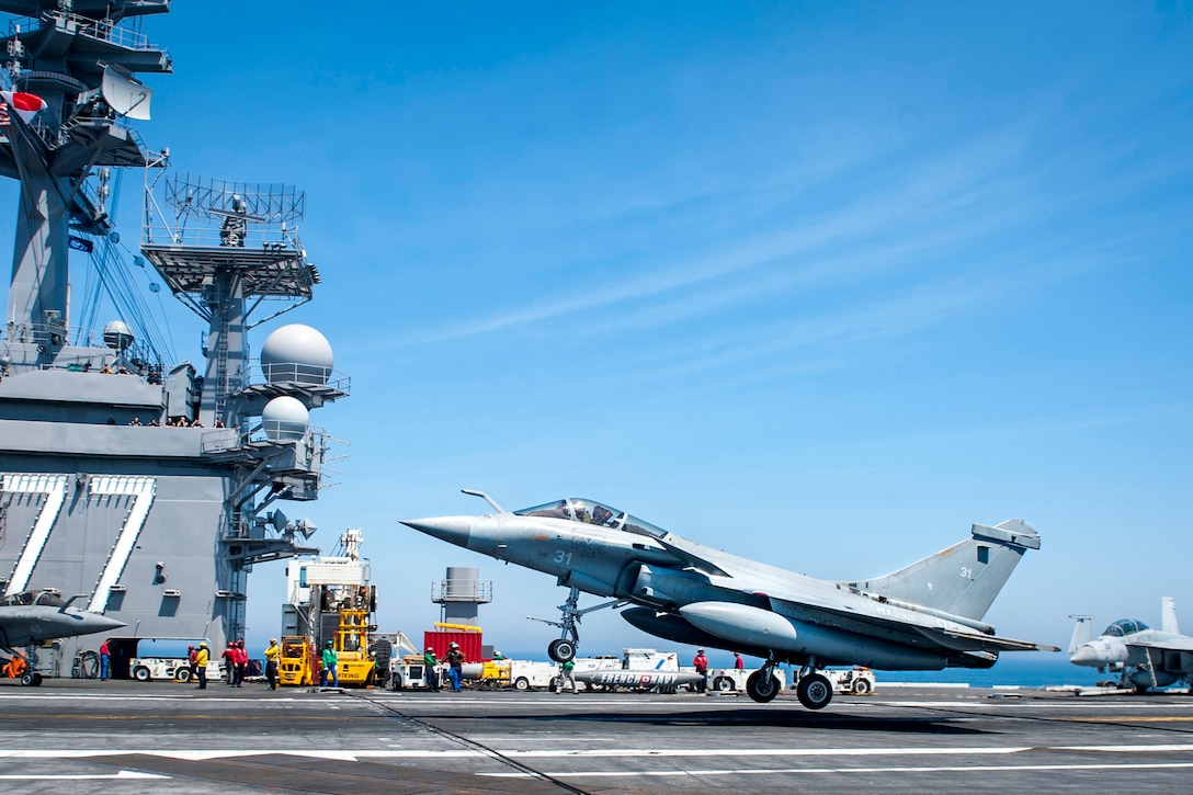 A military aircraft lands on an aircraft carrier.