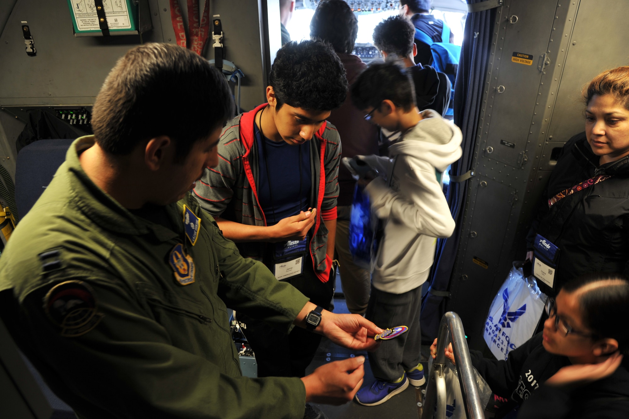 Capt. Lazare Quintana, C-17 Globemaster III pilot with the 313th Airlift Squadron, explains the elements of the squadron patch before handing it out to teenage students visiting the C-17 static display during the Alaska Airlines Aviation Day event May 5, 2018 at Seattle-Tacoma International Airport.