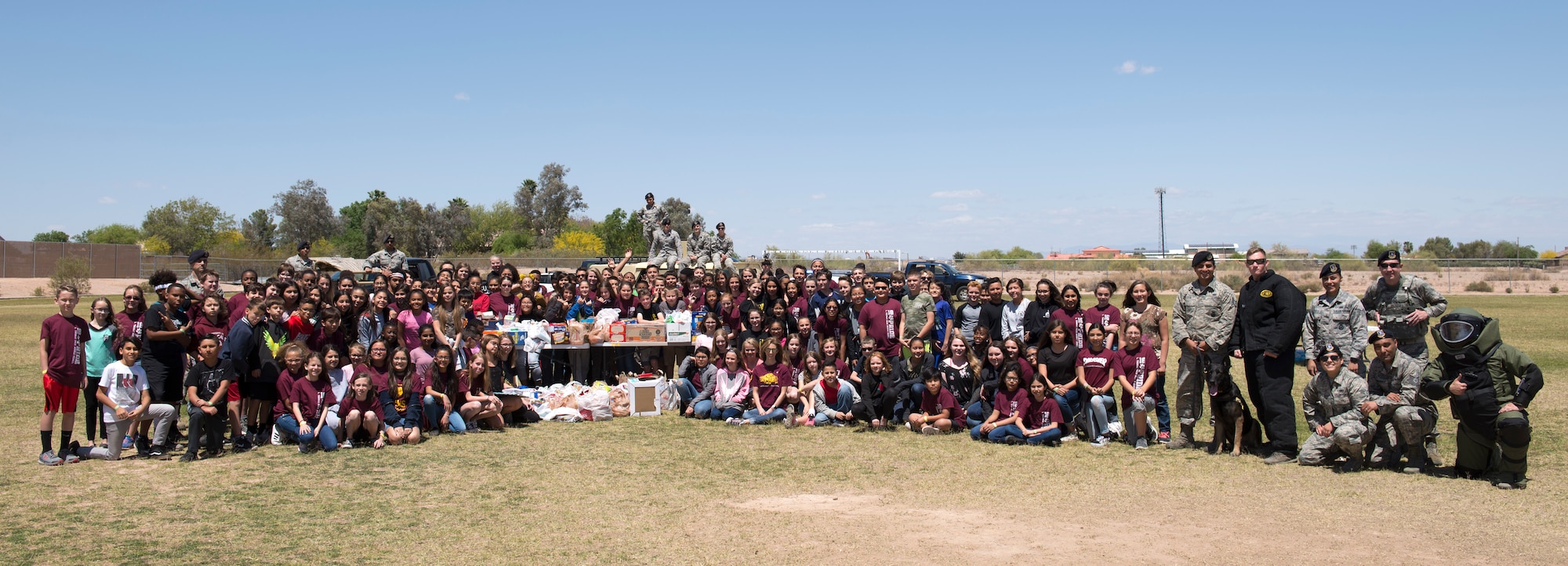 Members of L. Thomas Heck Middle School’s sixth-grade class pose for a photo with members of the 56th Security Forces Squadron and 56th Civil Engineer Squadron explosive ordnance disposal flight April 20, 2018, in Litchfield Park, Ariz. The table in the center contained food and entertainment items to be sent in care packages to deployed service members. (U.S. Air Force photo by Senior Airman Ridge Shan)