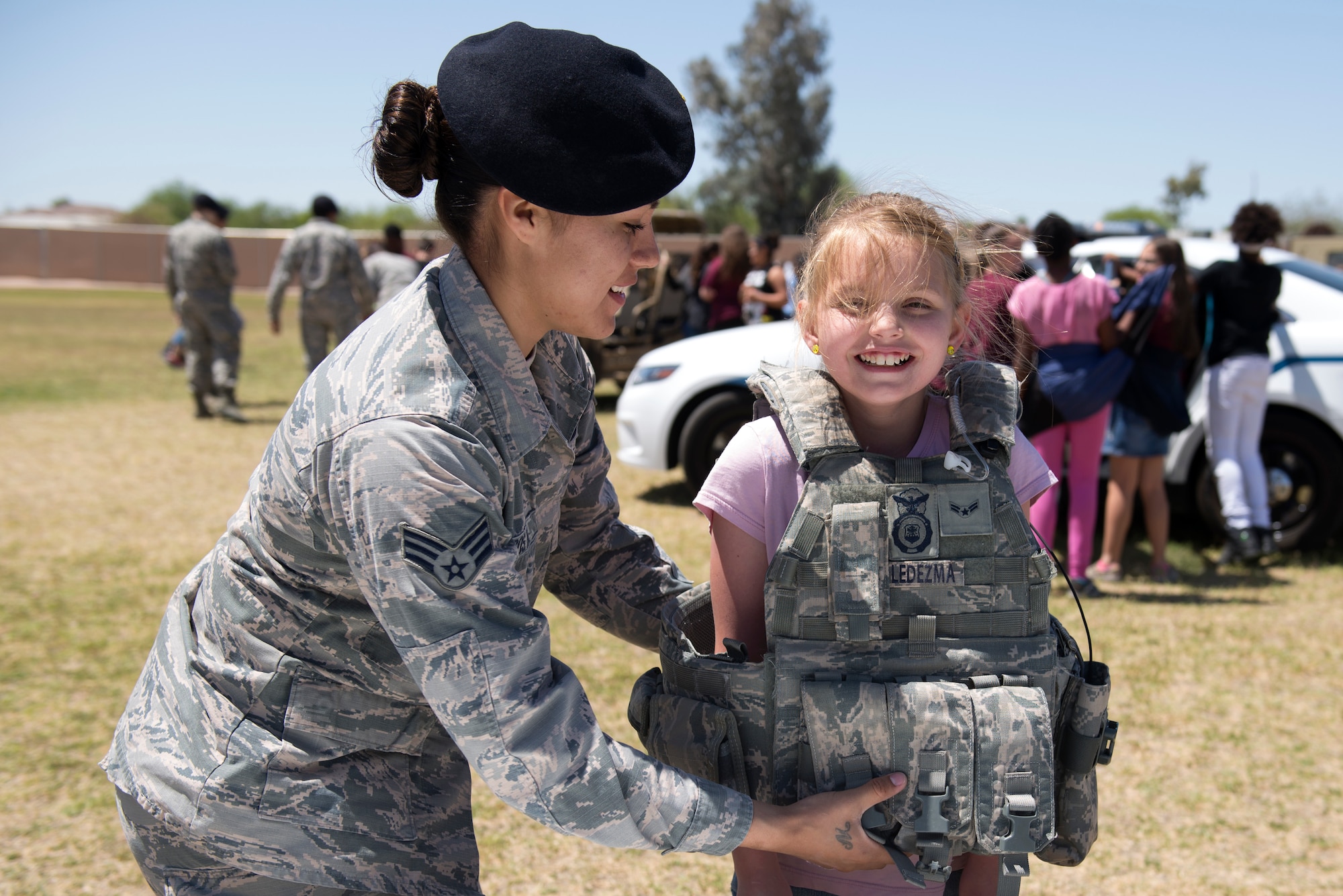 Senior Airman Melissa Ledezma, 56th Security Forces Squadron patrolman, helps a student from L. Thomas Heck Middle School try on her protective vest April 20, 2018, in Litchfield Park, Ariz. The 56th SFS brought vehicles, protective wear, and a military working dog to show off to students during their visit to the school. (U.S. Air Force photo by Senior Airman Ridge Shan)