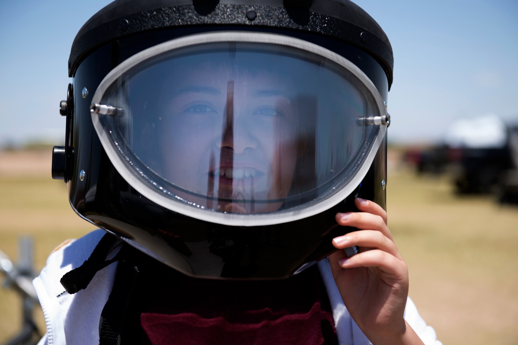 A student from L. Thomas Heck Middle School smiles through the visor of a 56th Civil Engineer Squadron explosive ordnance disposal bomb suit helmet April 20, 2018, in Litchfield Park, Ariz. Students could try on suits, uniform items, and other protective wear commonly used by Luke Air Force Base Airmen. (U.S. Air Force photo by Senior Airman Ridge Shan)